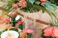 a chic retro tropical wedding tablescape with greenery, leaves and bold blooms, gold touches and cutlery