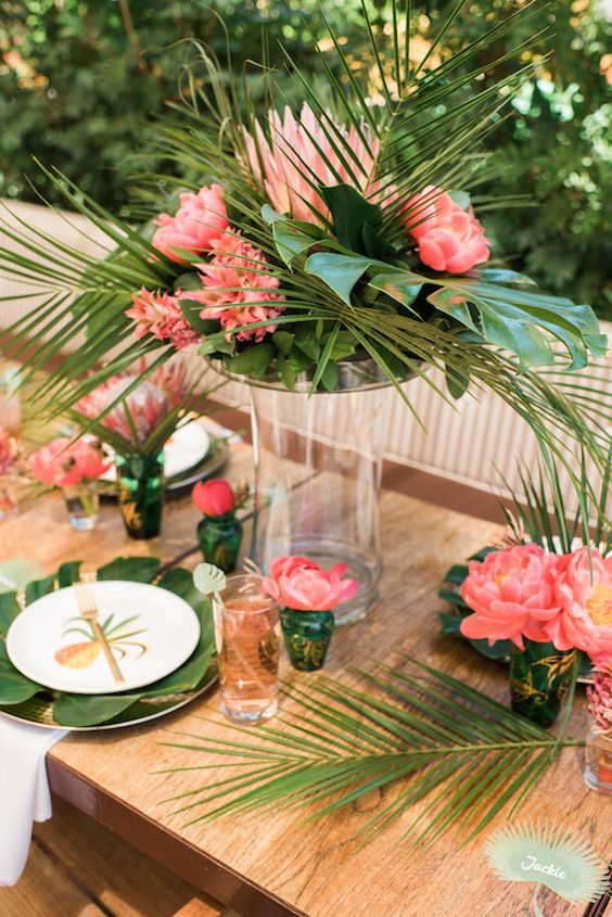 a chic retro tropical wedding tablescape with greenery, leaves and bold blooms, gold touches and cutlery