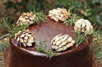 a chocolate wedding cake with almond pinecones, evergreens and served on a wooden slice is perfect for a modern woodland wedding