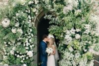 a church entrance decorated with greenery and white blooms looks chic and lush