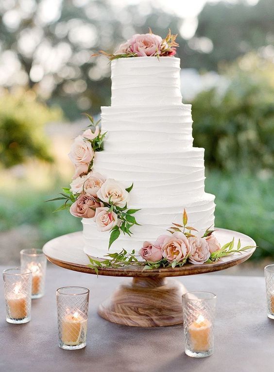 a classic textural white wedding cake with pink and blush blooms and foliage is a chic idea
