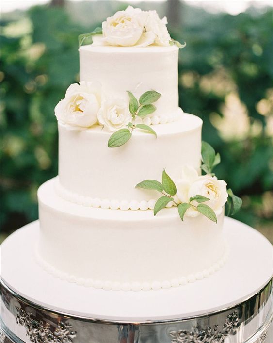 a classic white wedding cake with bead decor, foliage and white blooms is a very chic idea