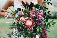 a colorful boho wedding bouquet in pink, fuchsia, with billy balls, greenery and some cascading elements