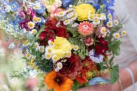 a colorful summer boho wedding bouquet in blue, yellow, pink, red and orange plus greenery