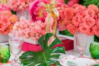 a colorful tropical wedding tablescape with pink blooms, gilded palm trees, pink placemats and colored glasses
