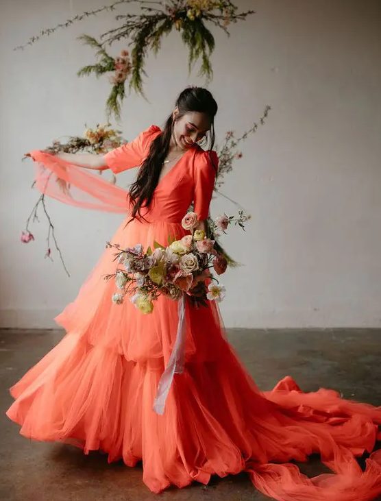 a coral A-line wedding dress with a deep V neckline, short puff sleeves and a tiered skirt plus a train for a colorful wedding