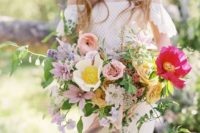 a creative textural boho wedding bouquet in bright pink, blush, marigold, purple and with lots of greenery