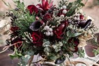 a dark and moody woodland wedding centerpiece with antlers, dark and deep red blooms and textural greenery and berries