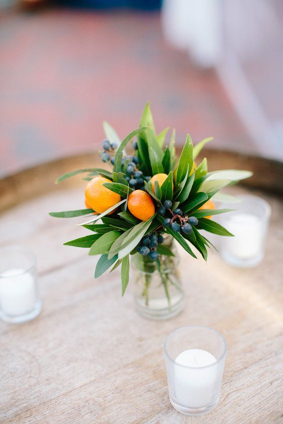 a delicate arrangement of kumquats, oranges, berries and leaves is a small and pretty decoration for a wedding