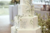 a delicate vintage-inspired wedding cake with blue flowers, greenery and some natural blooms on top