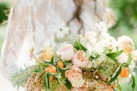 a delicate wedding bouquet of blush and orange blooms, greenery, kumquats and branches with berries is ideal for a spring or summer bride