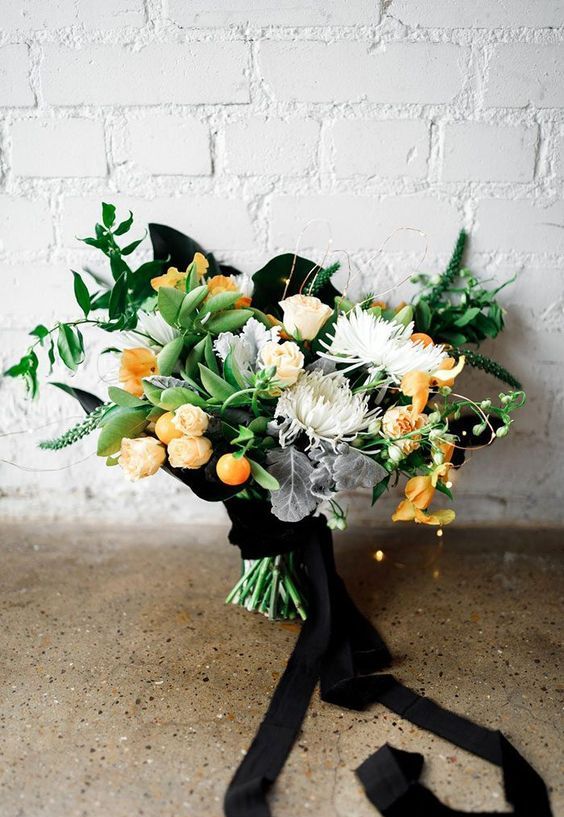a dramatic fall wedding bouquet of white blooms and orange ones, kumquats, greenery and pale leaves plus black ribbons is amazing