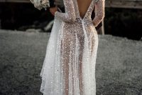 a fully embellished A-line wedding dress with a low back, long sleeves and a train is a veyr refined and chic idea to rock
