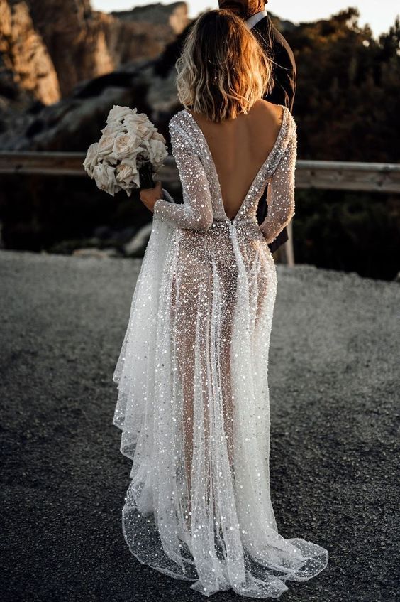 a fully embellished A-line wedding dress with a low back, long sleeves and a train is a veyr refined and chic idea to rock