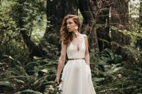 a gorgeous plain A-line wedding dress with a deep neckline, a shiny metallic belt and a pleated skirt with a long trian plus floral earrings
