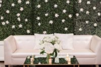 a greenery wall with white blooms that match the sofa create a cohesive lounge look