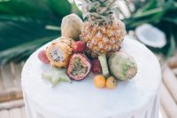 a lovely white wedding cake with drip, fresh tropical fruits including a pineapple is a beautiful and delicious option