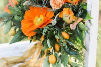 a lush and textural wedding bouquet of red and orange blooms, leaves and greenery and kumquats is a cool idea for summer