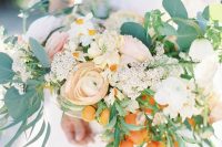 a lush wedding bouquet of white and blush blooms, greenery, kumquats and grasses is a very cool and pretty idea for a summer or spring wedding