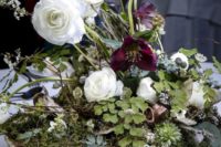 a lush woodland wedding centerpiece with moss, deep purple and white blooms and greenery