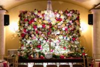 a luxurious bright floral wall is a gorgeous backdrop and a refined chandelier highlights it veyr much
