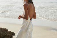 a minimalist flowy wedding dress with spaghetti straps and a sash plus a train for a modern or minimalist beach bride