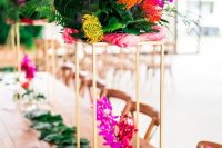 a modern colorful wedding tablescape with a leaf runner, bold blooms on tall stands and mini pineapples