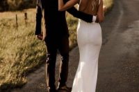 a modern plain mermaid wedding dress with a low back, spaghetti straps and a train plus a refined hat for a modern chic bride