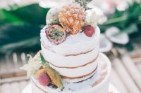 a naked wedding cake topped with fresh tropical fruits is a lovely and chic idea for a modern tropical wedding