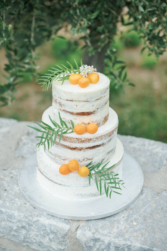 a naked wedding cake with kumquats, greenery and white blooms is a lovely wedding dessert idea to try