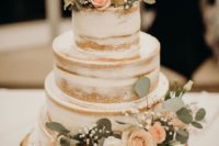 a naked wedding cake with white and blush blooms, baby’s breath, foliage and wire toppers