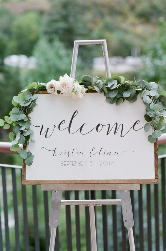 a neutral wedding sign with wooden framing and greenery and neutral blooms is a simple and stylish idea