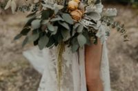 a pale boho wedding bouquet of pale greenery, rust blooms, leaves for a summer or fall bride