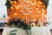 a pallet backdrop with lights, greenery and bright blooms and your couple’s names on the wall