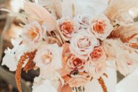 a pastel boho wedding bouquet in blush, light pink, white, with pampas grass and pink ribbons hanging down