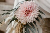 a pastel boho wedding bouquet of a large blush bloom, dried spikes and pale palm leaves