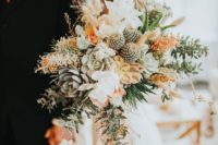 a pastel boho wedding bouquet of succulents, cacti, rust blooms, greenery and leaves for a desert bride