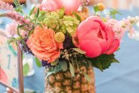a pineapple vase with bold blooms and greenery is an ideal option for a modern and bright tropical wedding