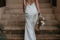 a plain flowy wedding dress with spaghetti straps and a train plus a low back is a perfect idea for a modern summer bride