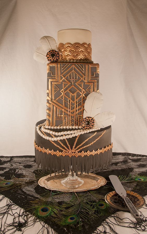 a refined art deco wedding cake in black, white and gold, with geometric patterns, beads and feathers