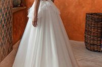 a refined princess-style wedding dress with a fringe and lace applique boidce, a low back and a layered full skirt witha train for a formal wedding