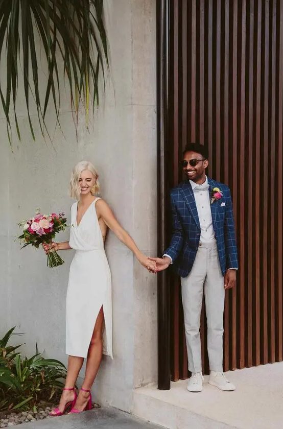 a simple and cool white midi wedding dress with a V neckline, thick straps, a side slit, pink ankle strap shoes is wow