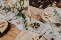 a simple woodland wedding table setting with wood slices, simple wildflowers and touches of gold here and there