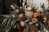 a summer or fall boho wedding bouquet of rust-colored blooms, white blooms and lots of greenery