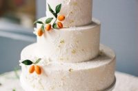 a tan textural and painted wedding cake with gold foil, kumquats is a gorgeous idea for a wedding in summer