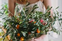 a textural and large wedding bouquet of lots of greenery, berries and kumquats looks very cool and very Mediterranean-like