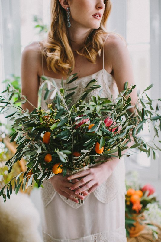 a textural and large wedding bouquet of lots of greenery, berries and kumquats looks very cool and very Mediterranean-like