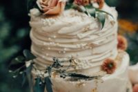 a textural vintage-like wedding cake with different tiers, beads, gold leaf and rust-colored blooms and foliage
