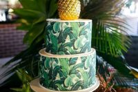 a tropical leaf print wedding cake with a gilded pineapple on top is a very bright and cool idea for a modern bold wedding