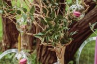 a whimsy woodland wedding centerpiece of a tree with foliage, glass bubbles with moss and pink macarons
